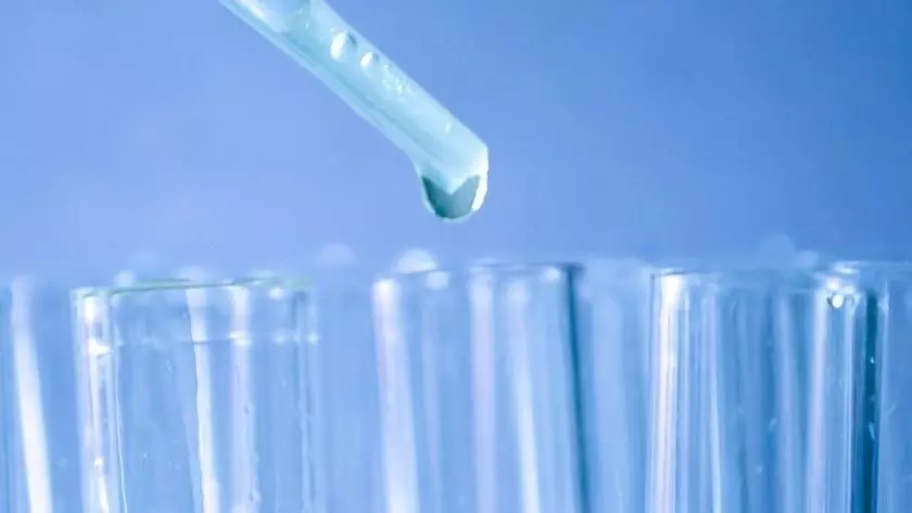 Pipette dropping liquid into colourful test tubes
