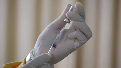 Hands in white gloves holding a syringe